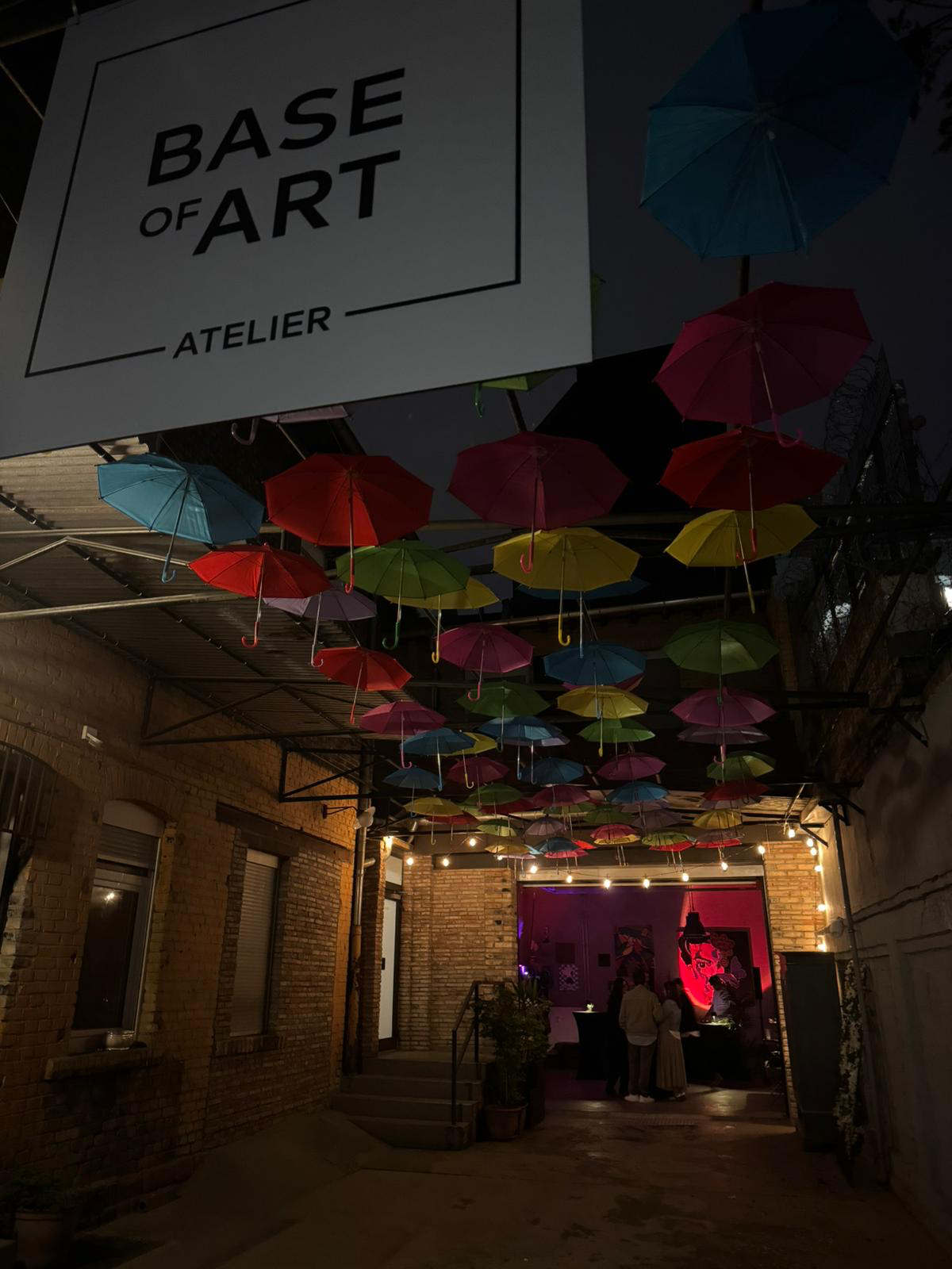 Atelier bei Nacht — bunte Regenschirme über dem Innenhof