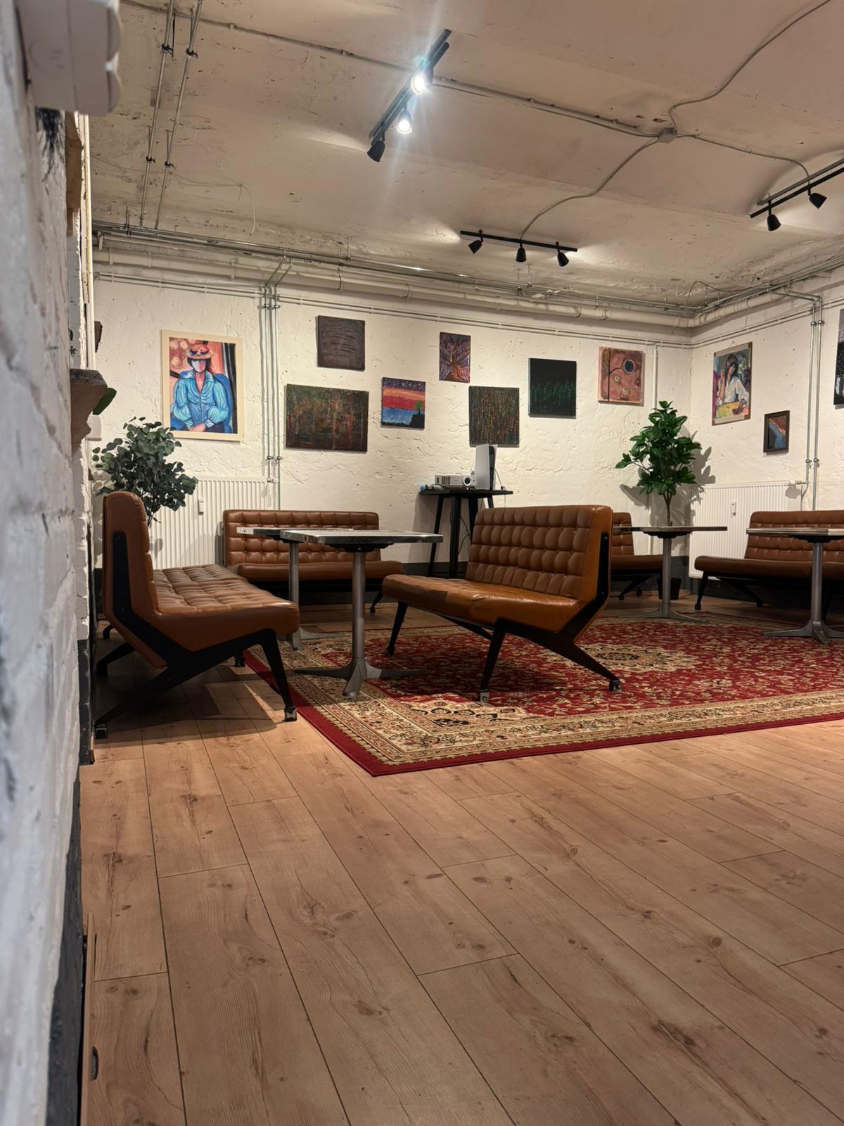 Atelier-Lounge mit Sesseln, Teppich und Galerie-Wand